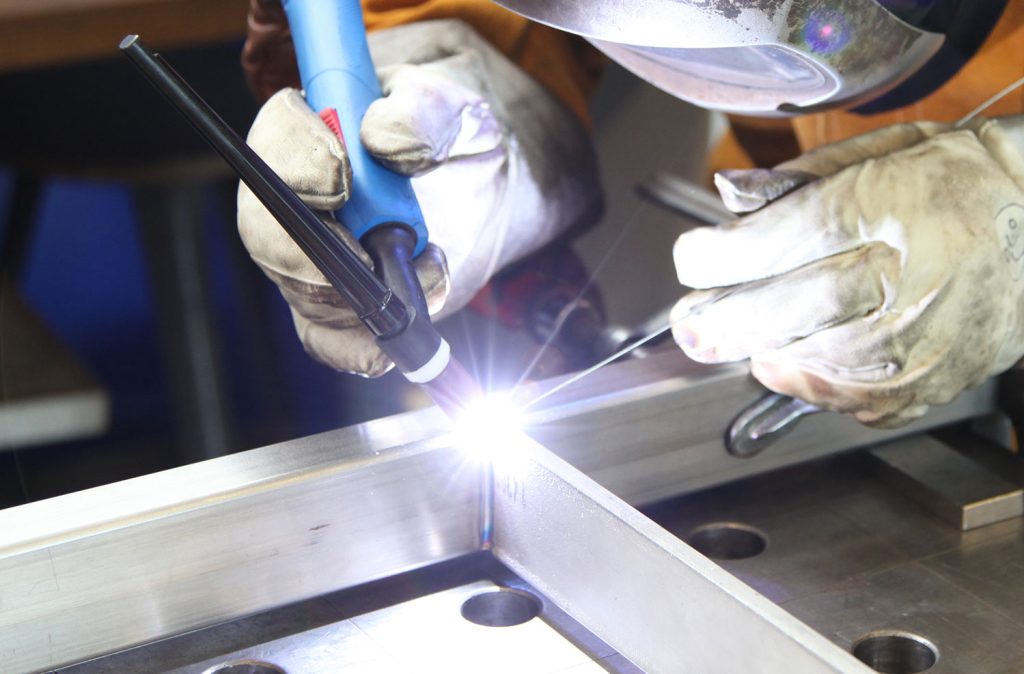 A person skillfully welding metal with a torch, sparks flying, showcasing craftsmanship and focus in their work.