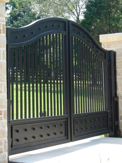 A Black Gate With A Brick Wall And Trees In The Background